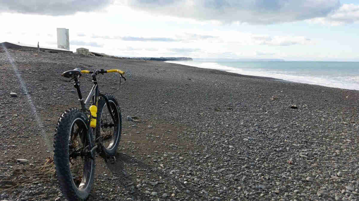 Rear view of a Surly Pugsley fat bike, parked on a vast, rocky seashore