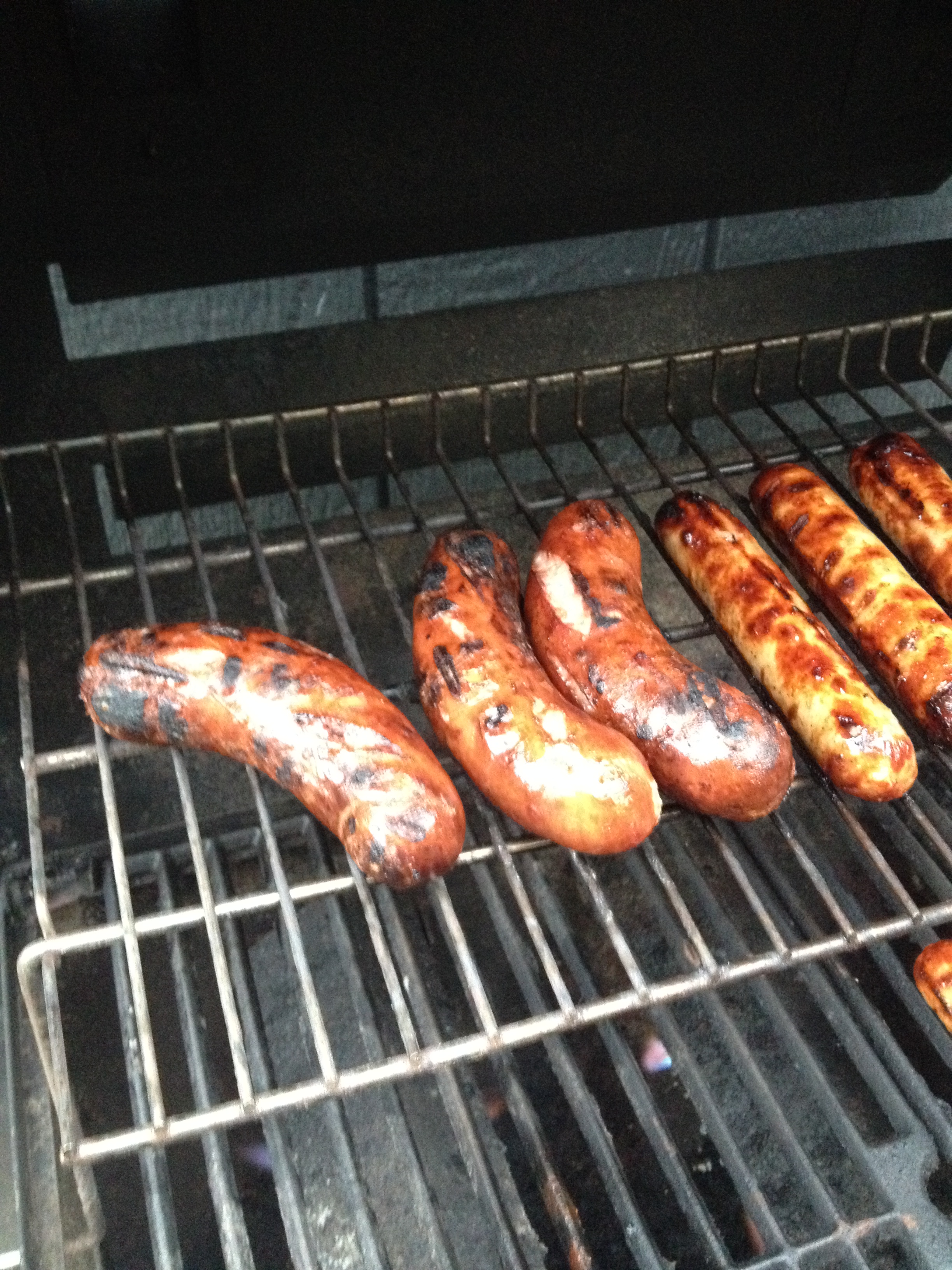 Brats on a the top rack of a gas grill