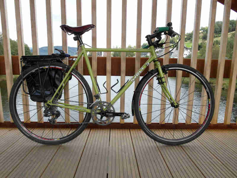 Right profile of Surly bike, green, parked on a bridge over a river, alongside the rail