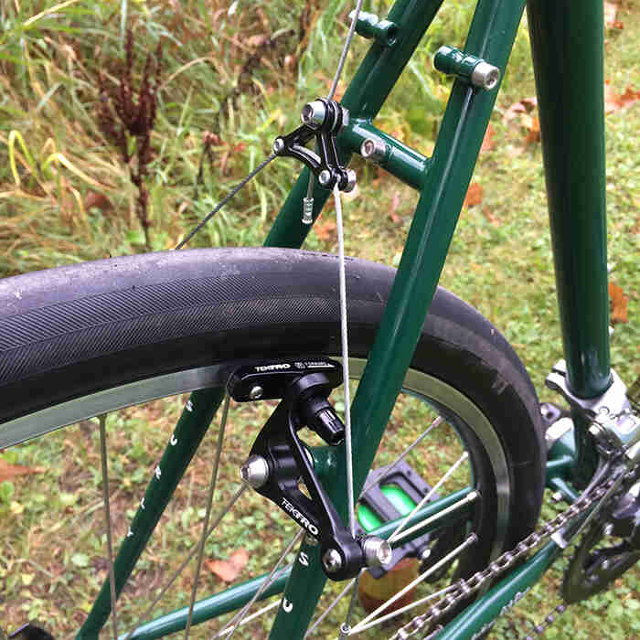 Right side view of the rear end of a green Surly Pack Rat bike, with focus on the brakes