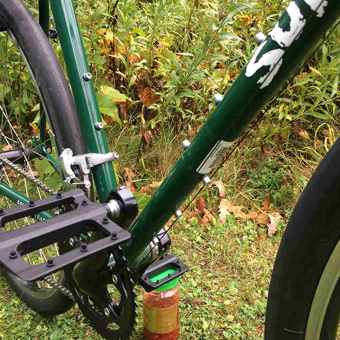 Angled, close up view of the crankset and the bottle cage mounts on the right side of a green Surly Pack Rat bike