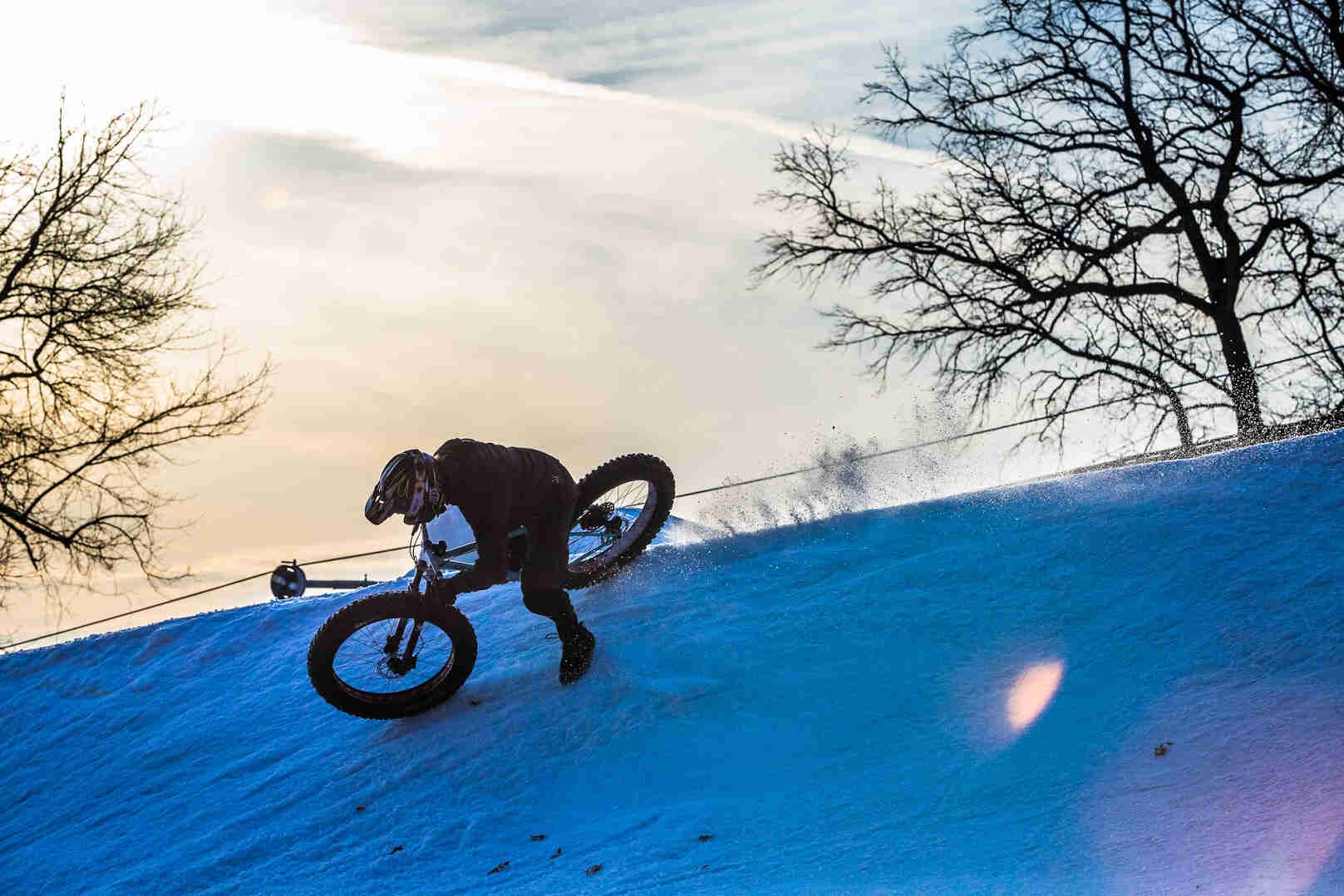 A cyclist riding a Surly Wednesday fat bike down the side of a snow half pipe at Buck Hill ski area