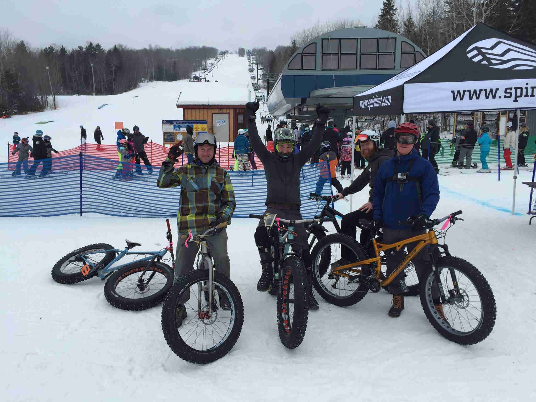 Front view of 3 cyclist on Surly Wednesday fat bikes, standing on snow at the base of a ski hill