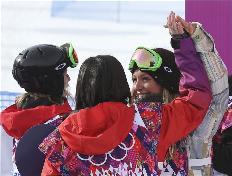 Three people wearing helmets and ski goggles, holding hands above their heads