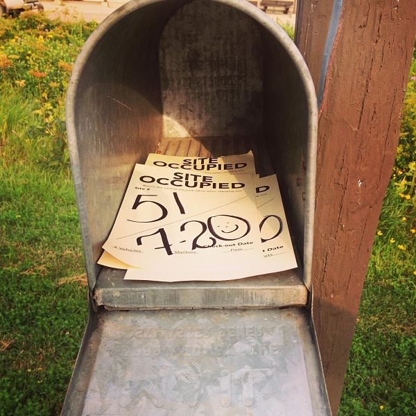 Front close up view of an open mailbox, with campsite occupation flyers inside