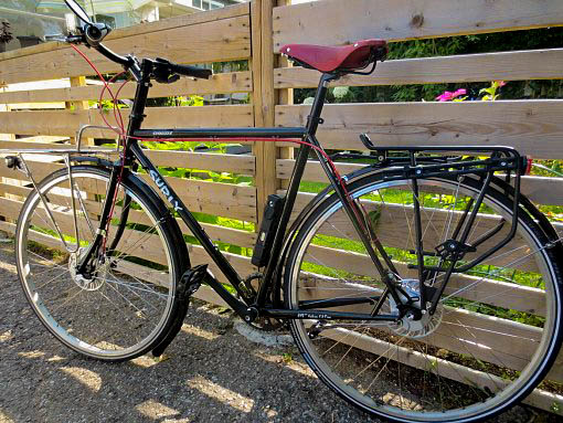 Left side view of a black Surly Straggler bike, parked along a wood fence