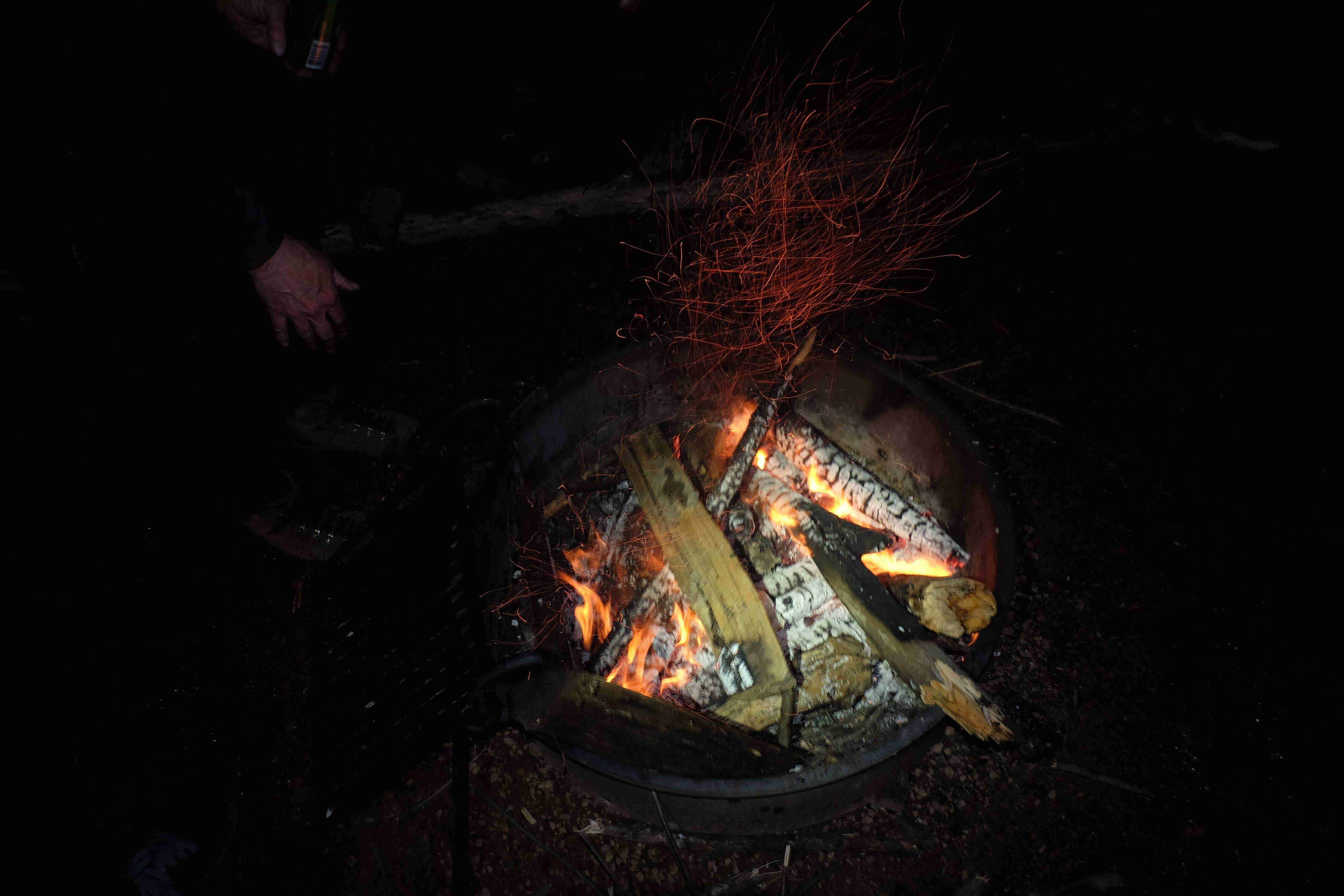 Downward view of a fire ring with a burning logs, in the dark at night