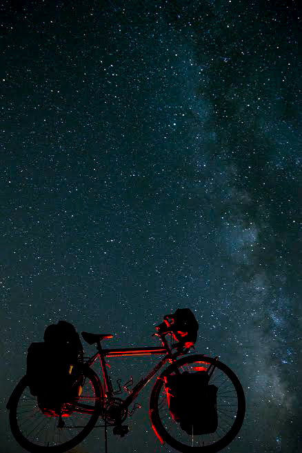 Silhouette of the right profile of a Surly bike, loaded with gear, under the stars at night