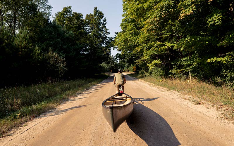 View from behind cyclist on gravel road towing canoe with Surly Bridge Club