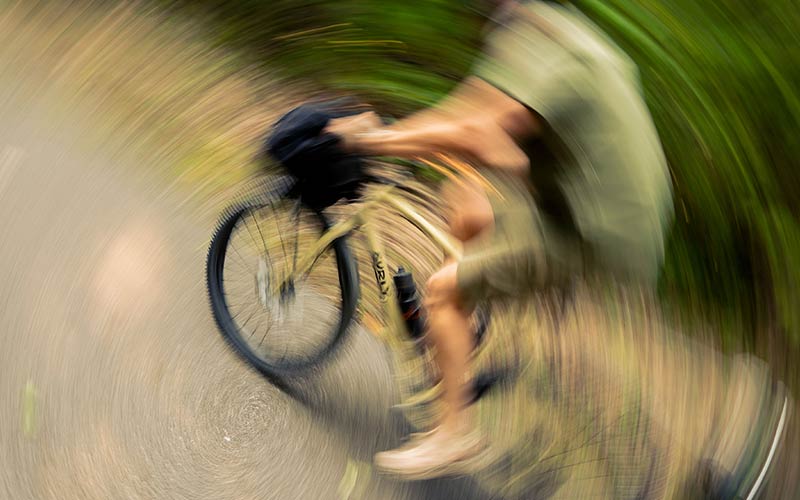 Circluar pan image effect of cyclist riding loaded Surly Bridge Club on gravel road