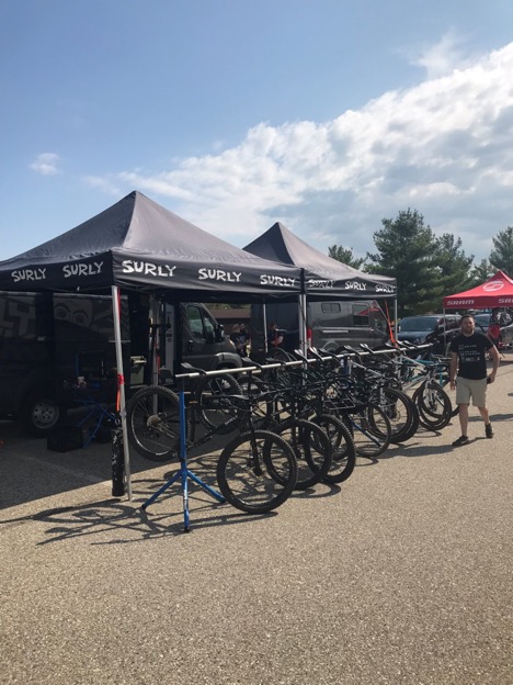 Bikes line up in front of two Surly pop up canopies on a paved lot