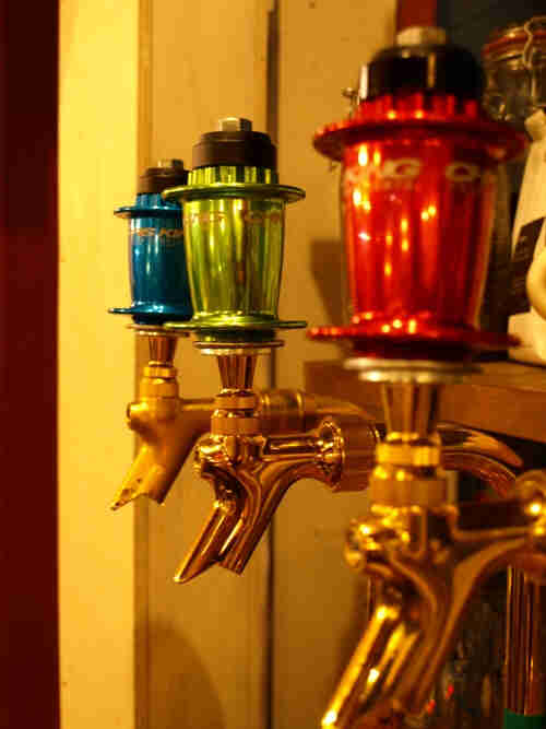 Side view of 3 beer taps, colored in red, green and blue, lined up side by side