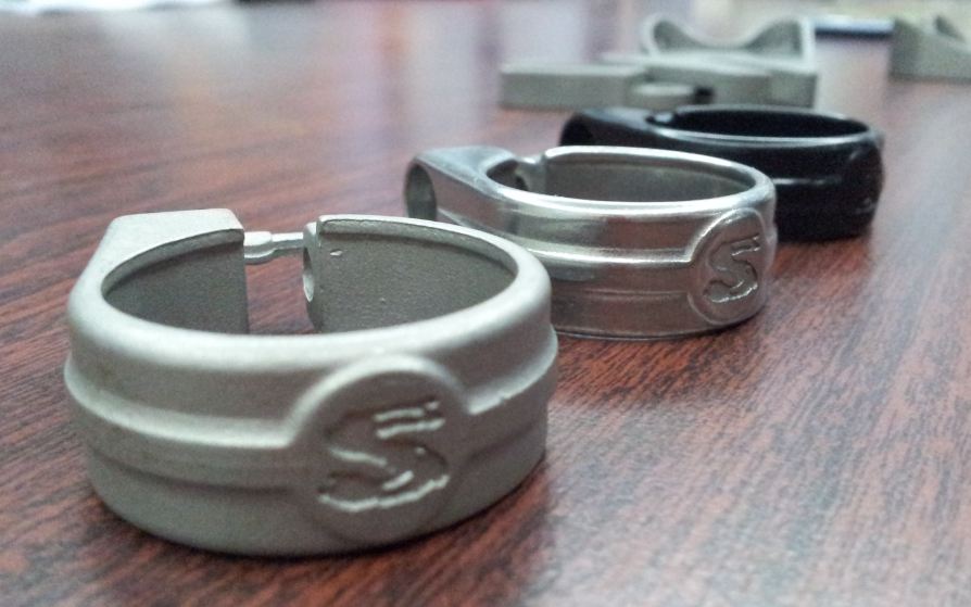 Side view of a row of Surly unpolished, stainless steel, bike seat collars, sitting on a table