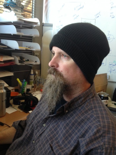 Head shot - Left side view of a person with a beard, wearing a black Surly Wool Beanie