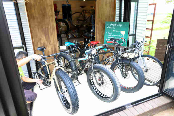 Front view of Surly fat bikes, lined up side by side, in front of an open door of a bike shop