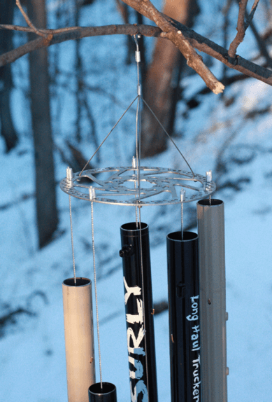 Close up view of a wind chime made from Surly bike parts, on a tree branch hovering over snowy ground