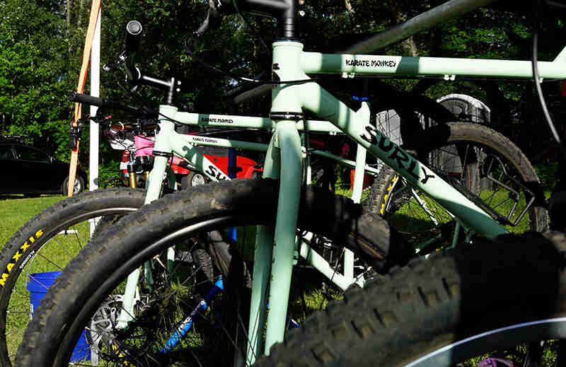 Cropped view of a row of mint Surly Karate Monkey bike front ends, with trees in the background