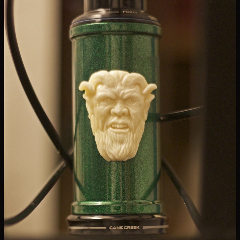 Close up, front view of the head tube of a green Surly bike with a Krampus face emblem on it