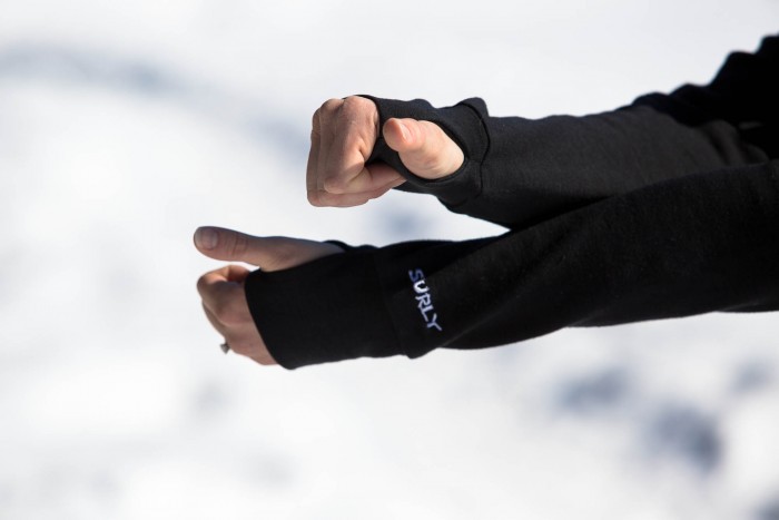 Person holding out their arms, showing thumb hole detail on their Surly Long Sleeve Jersey - blurry white background