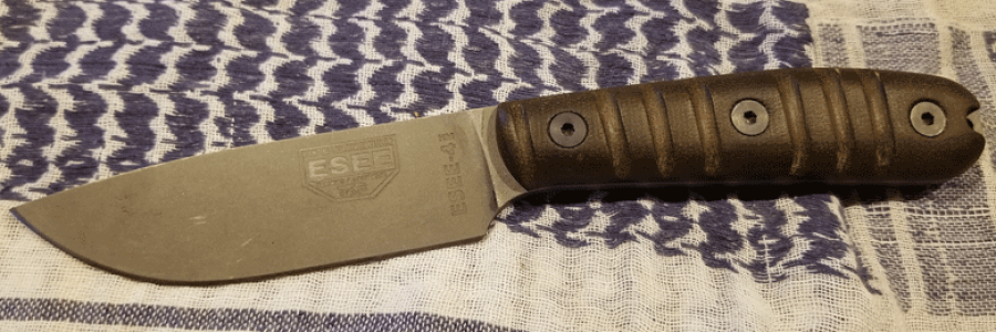 ESEE Knife with gray blade and wood handle laying on a blue and white woven blanket
