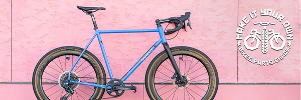Surly Midnight Special Bike with Perry Winkle’s Sparkle color on a sidewalk leaning on a pink stucco wall