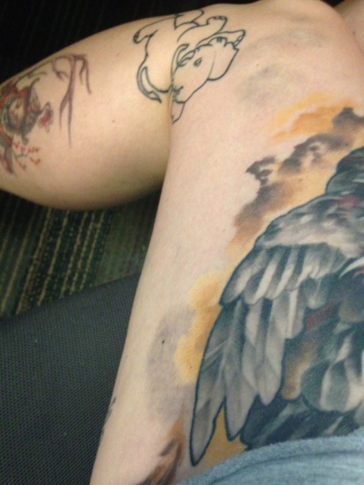 Downward view of a persons left leg with a bruise and tattoos on it