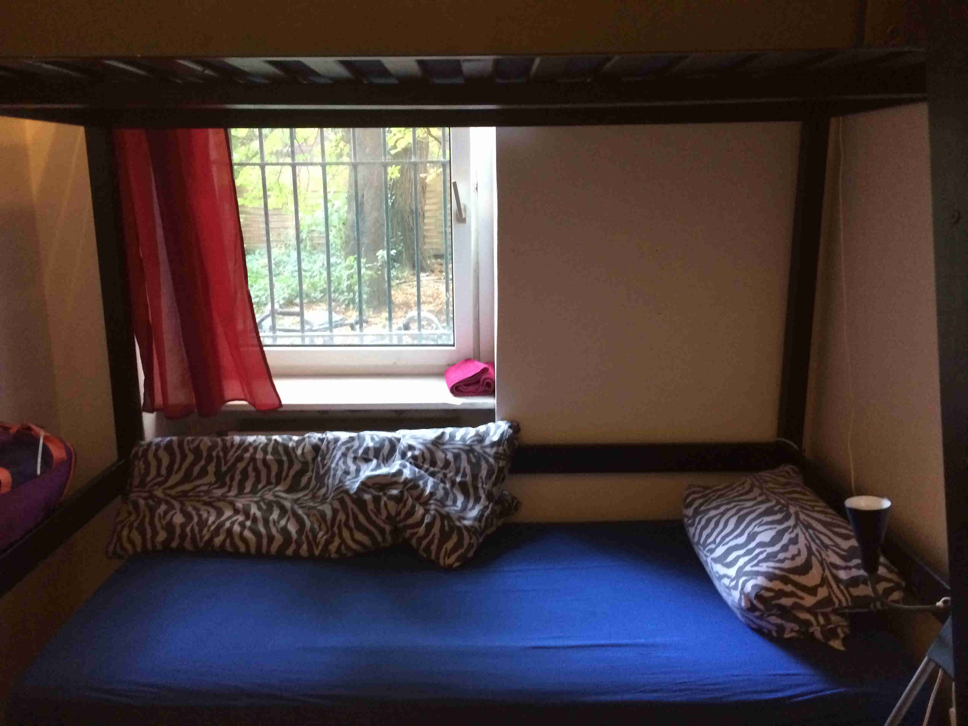Side view of a the bottom bunk of a bunk bed, in a small room with a window