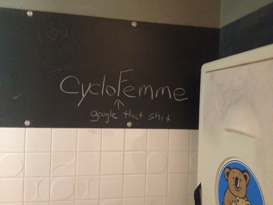A bathroom wall with a chalkboard on it, with the words, CycloFemme, above, and gargle that shit, written below