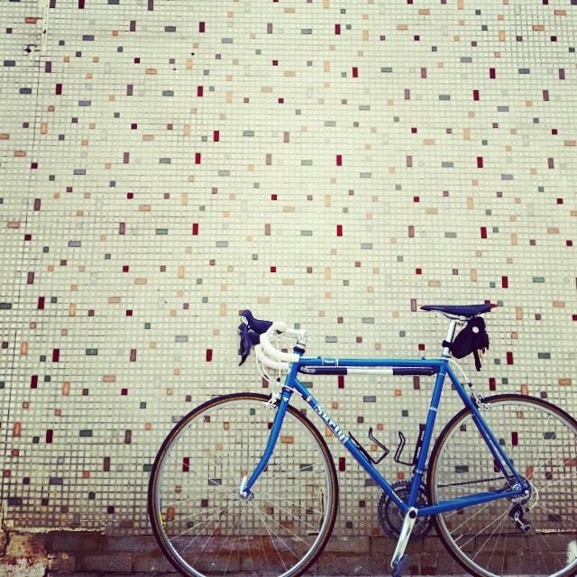 Left side view of a blue Surly Pacer bike, parked along a tiled wall