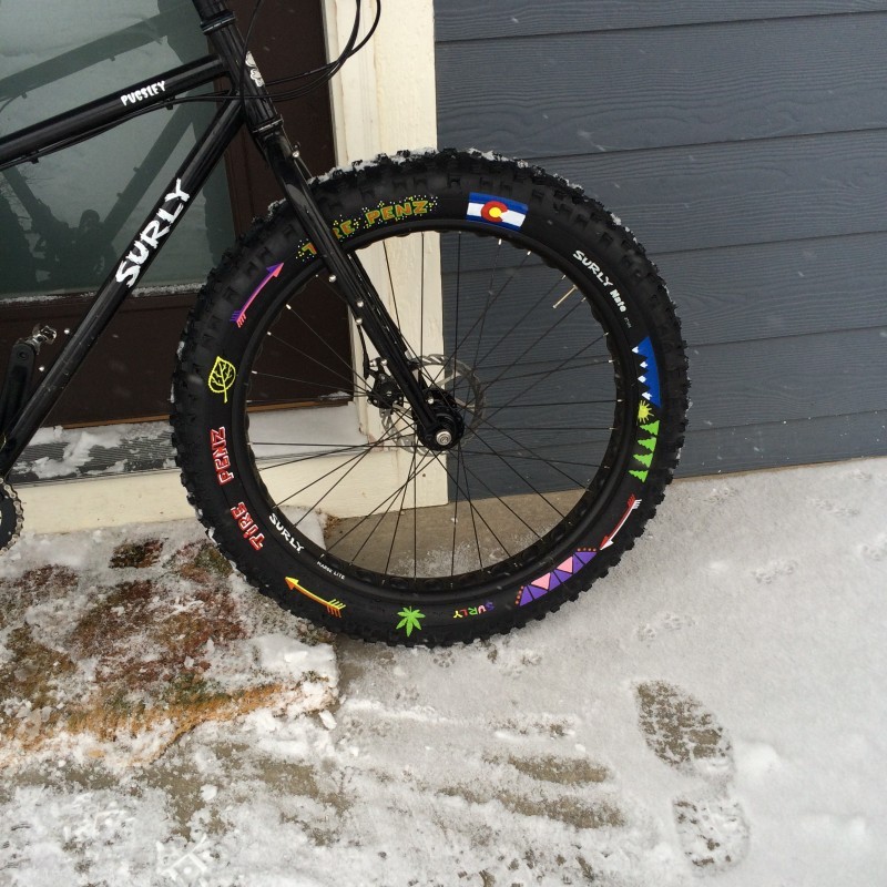 Right side, front half view of a black Surly Pugsley fat bike, parked in front of a house on the snowy porch