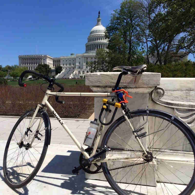 Left side view of a Surly bike, parked on a sidewalk against a cement barrier, with the US Capitol in the background