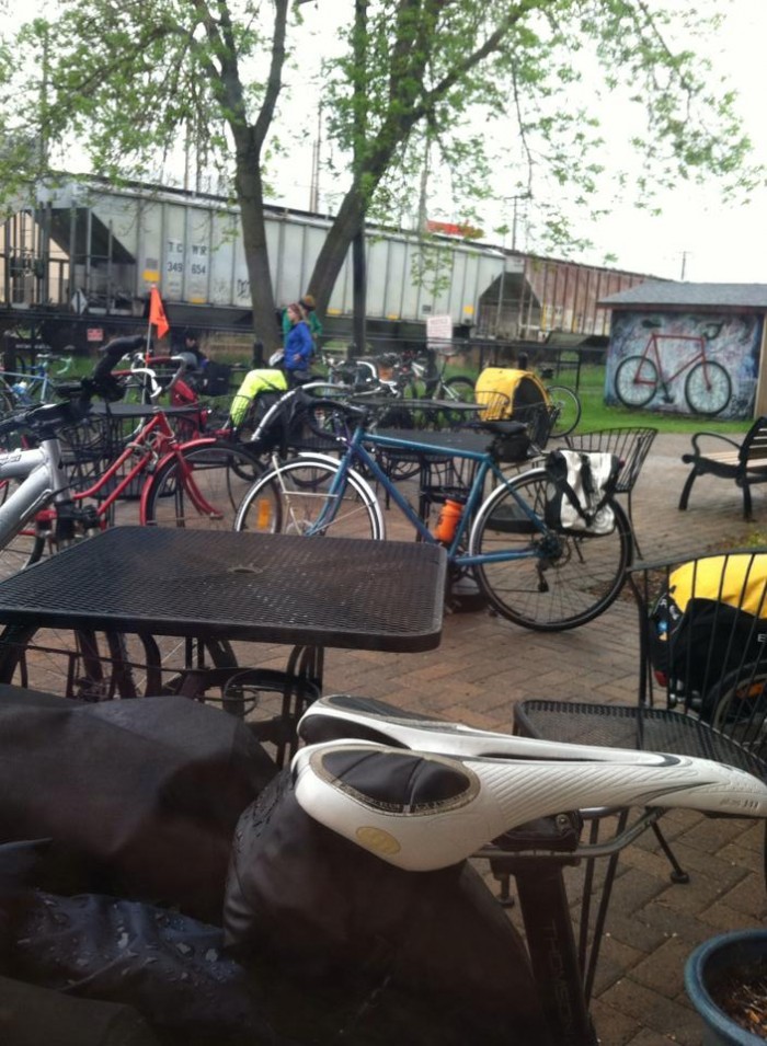 A patio area with tables and bikes, with train rail cars in the background