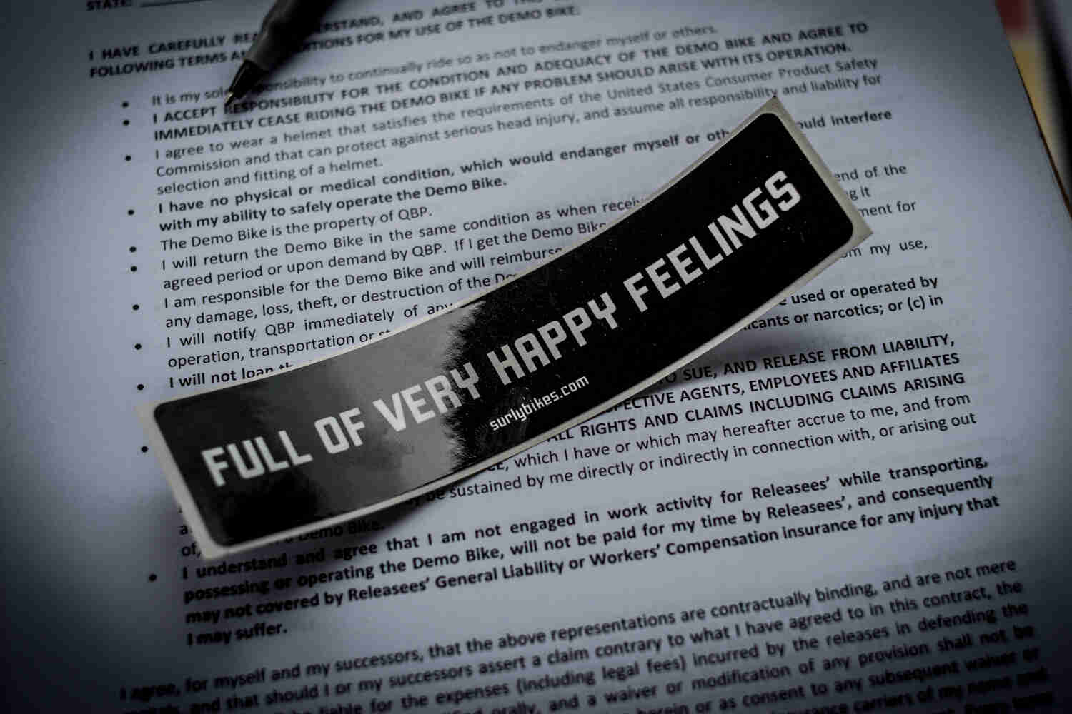 Close up view of a general release form with a Surly Bikes sticker that shows, FULL OF VERY HAPPY FEELINGS, on the top