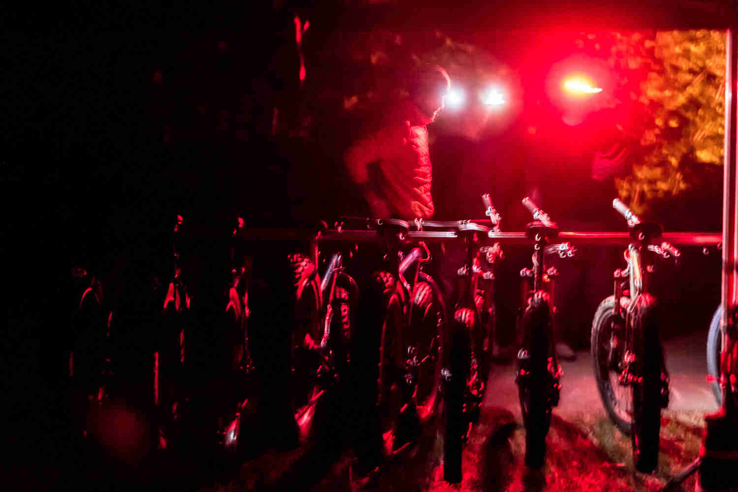 Rear view of a row of Surly fat bikes, at night, with a cyclist standing behind, in a red glow