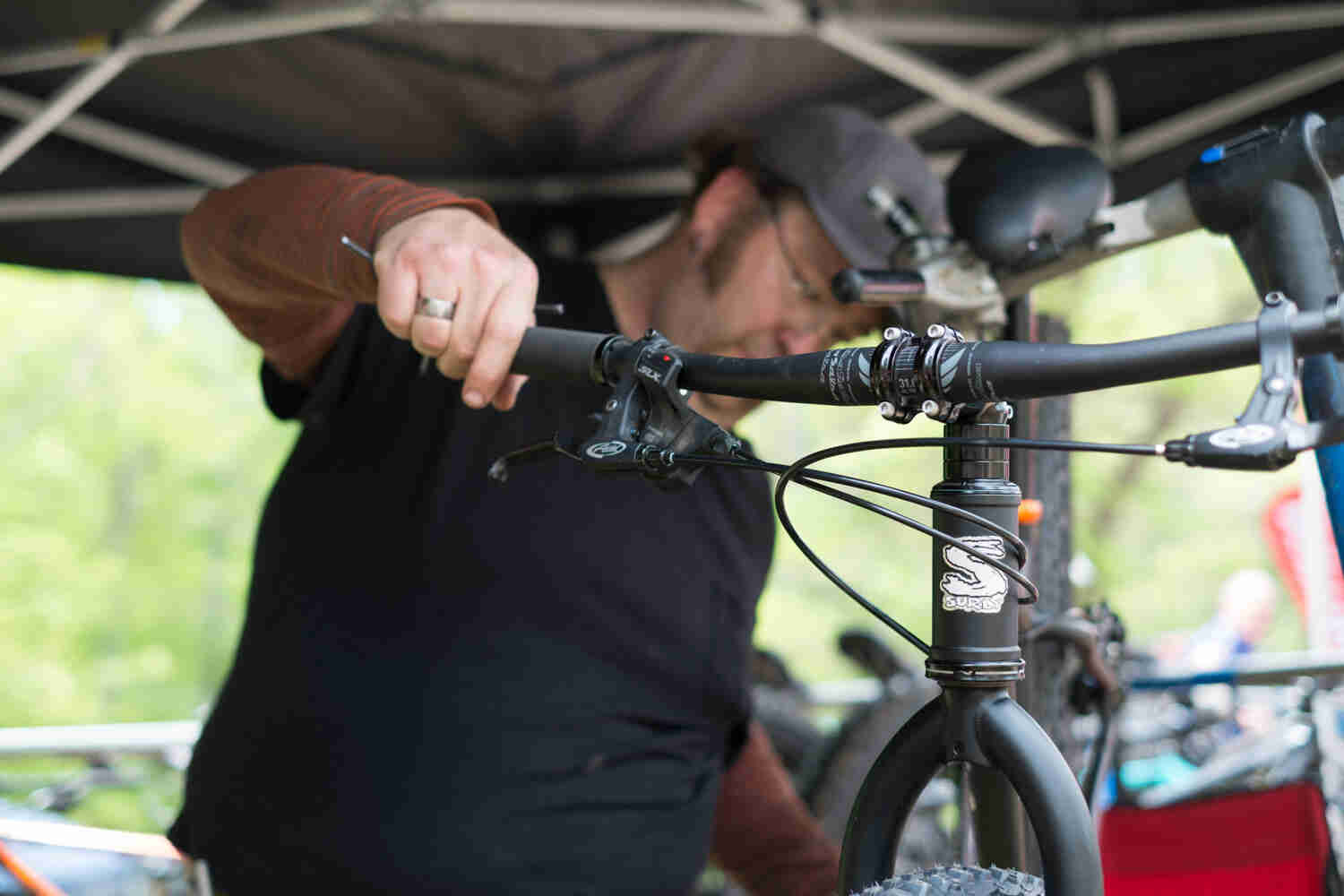 Cropped, front view of a person holding one of the handgrips of a black Surly fat bike