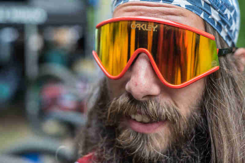 Front view of a person with a beard and mustache, wear Oakley mirrored sunglasses