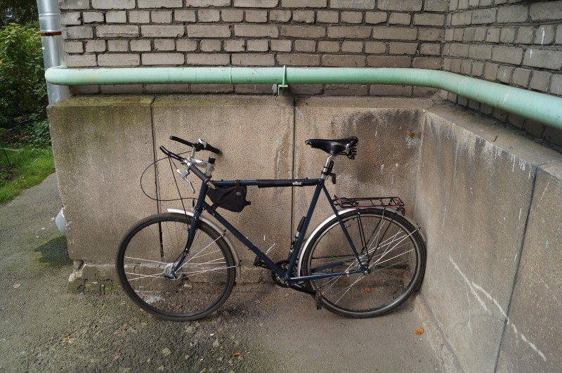 Left profile of a Surly bike leaning on a wall, outside of a brick building