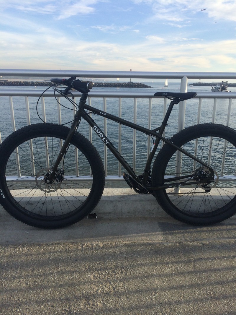 Left side view of a black Surly ECR bike, parked along a steel handrail with a bay behind it