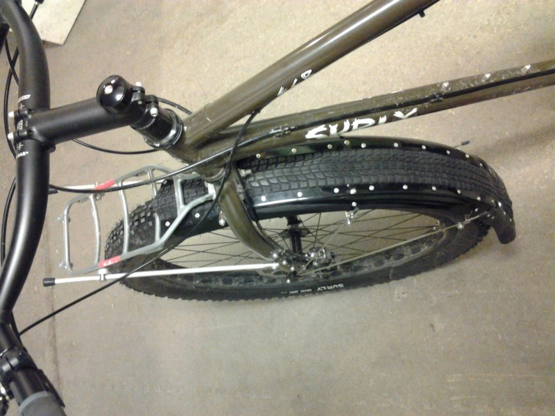 Downward view of the front end of an olive drab Surly ECR bike with fender and front rack