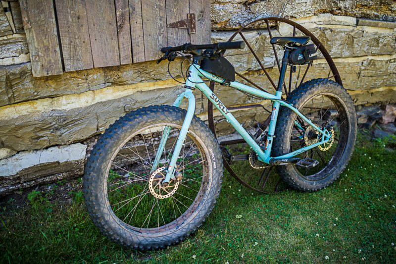  Left side view of a Surly Wednesday MY17 fat bike, mint leaning on the stone wall of a building