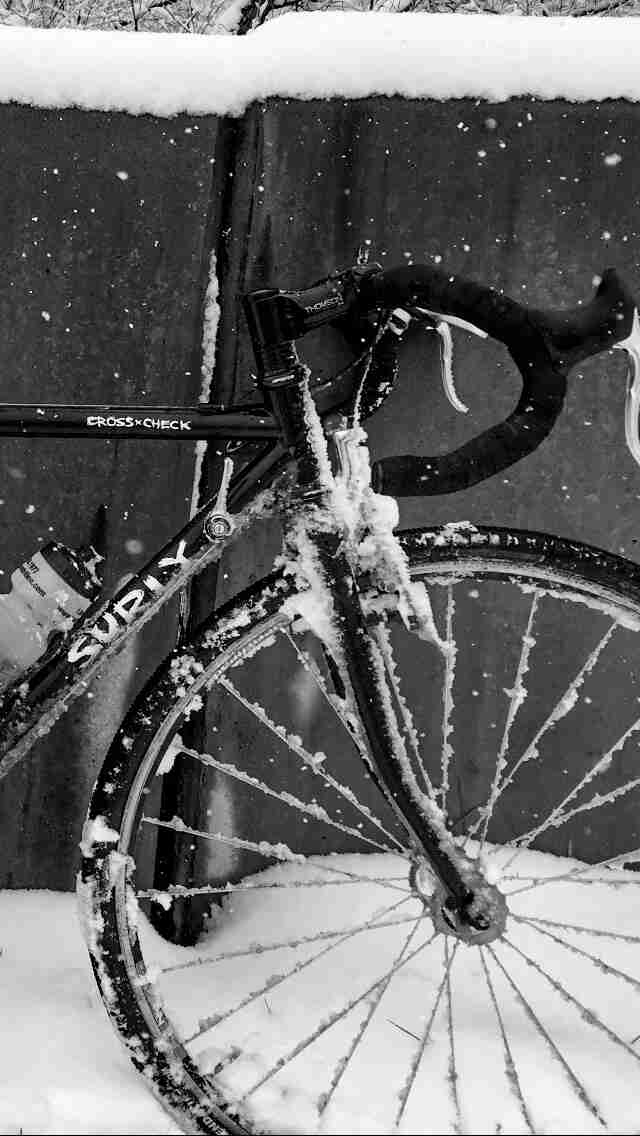 Cropped front right side of a Surly Cross Check bike, black, covered in snow - black & white image