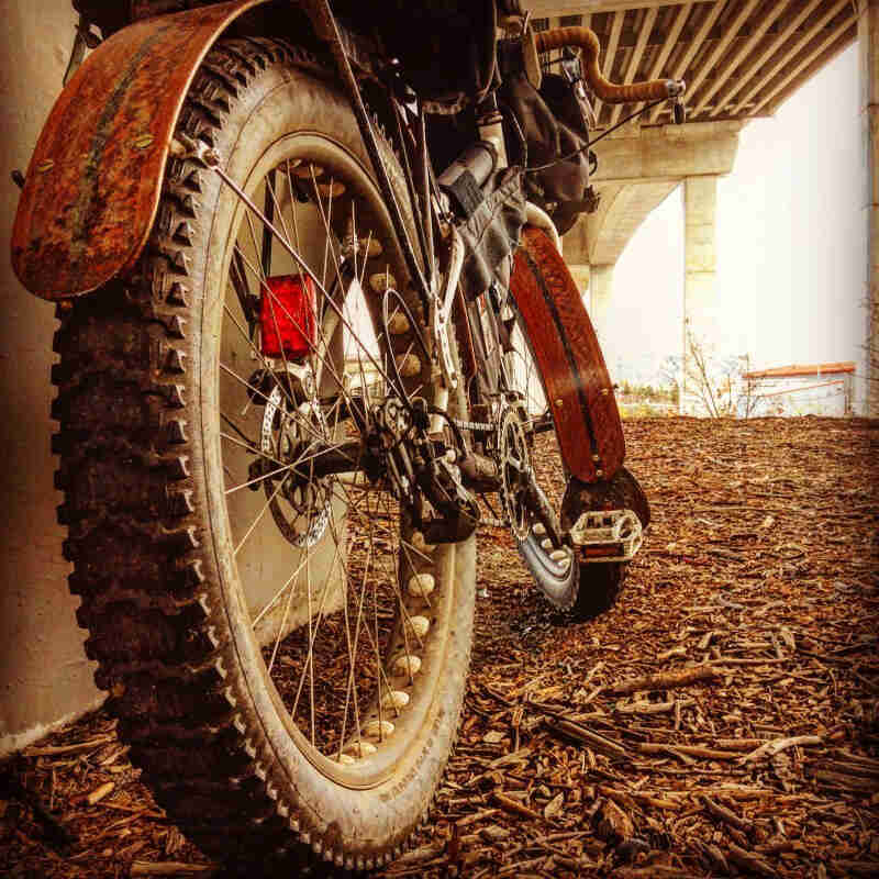 Rear, low view of a fat bike with fenders, parked under a concrete bridge