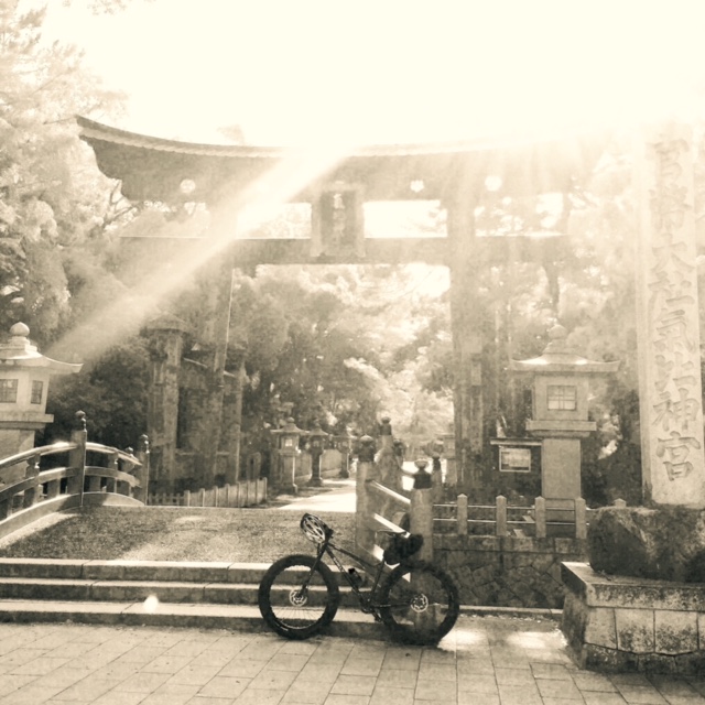 Black and white image - Left side view of a Surly Fat bike in front of a bridge at an asian style archway