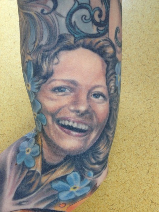 A person's leg with a colored, portrait tattoo, of a person's face