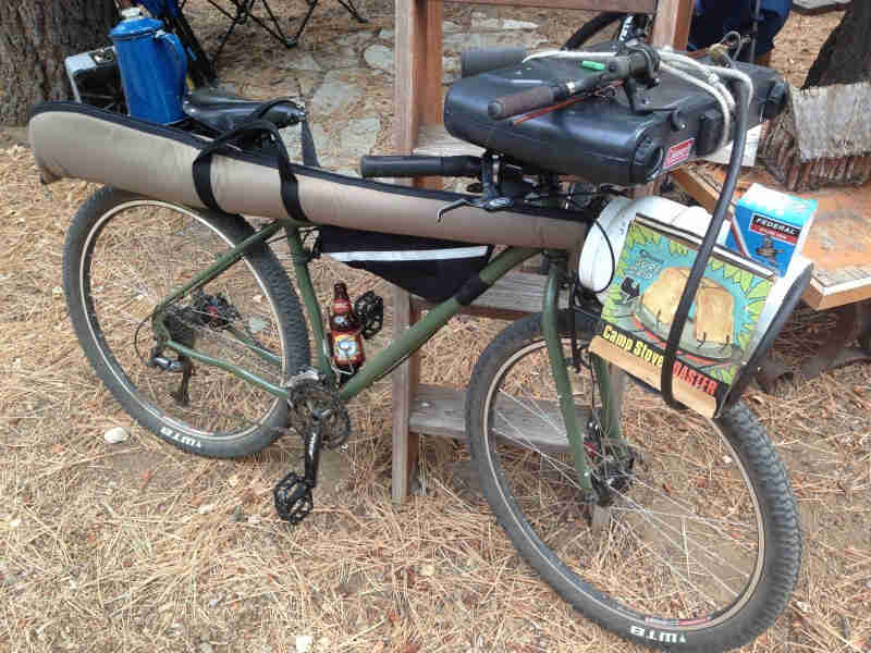 Right side view of a Surly Ogre bike with a gun case hanging from the seat and briefcase strapped to the handlebar