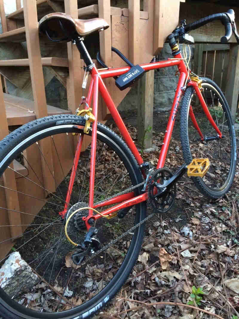 Right side view of a red Surly Pacer bike, parked against the stair balusters, on the outside of a wood deck