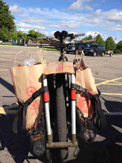 Rear view of a Surly Big Dummy bike, with groceries in the rear bags, in the middle of a paved parking lot