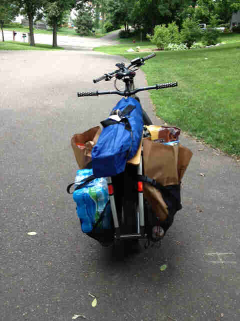 Rear view of a Surly Big Dummy bike, with groceries on the back, facing down a paved, neighborhood street