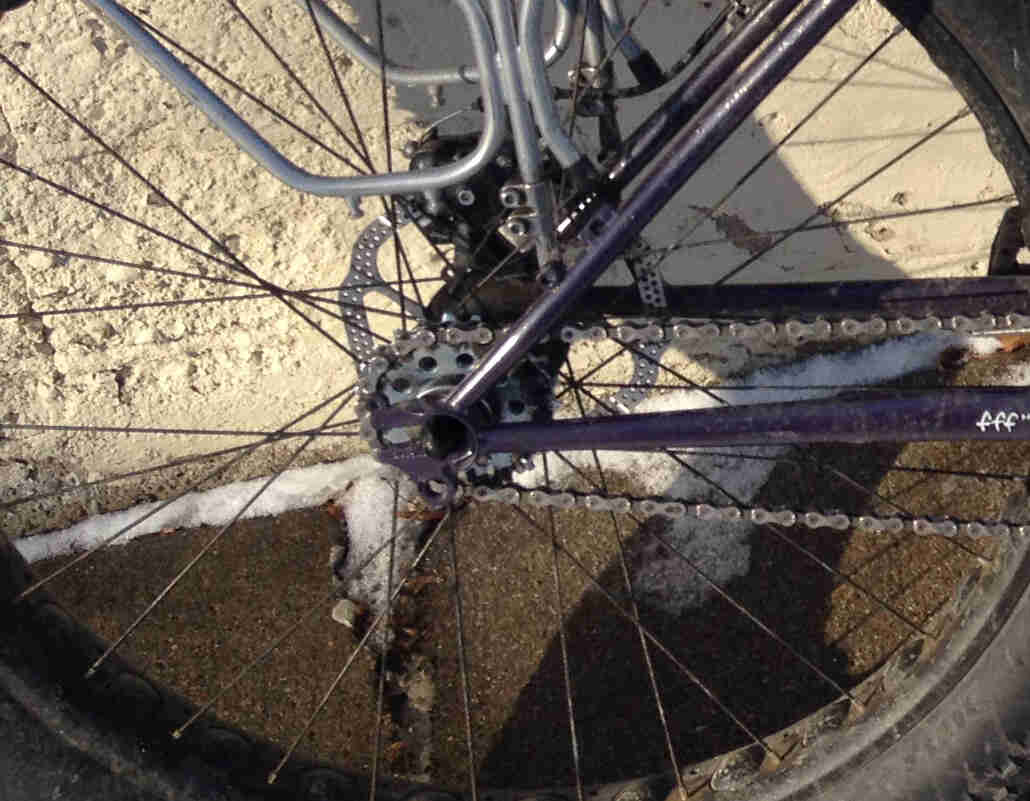 Downward close up view of a rear wheel, with a flip-flop hub, on a purple Surly Pugsley fat bike