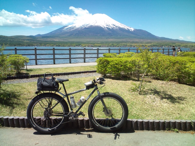 Right side view with a black Surly Pugsley fat bike with gear, with a lake and Mt. Fuji in the background